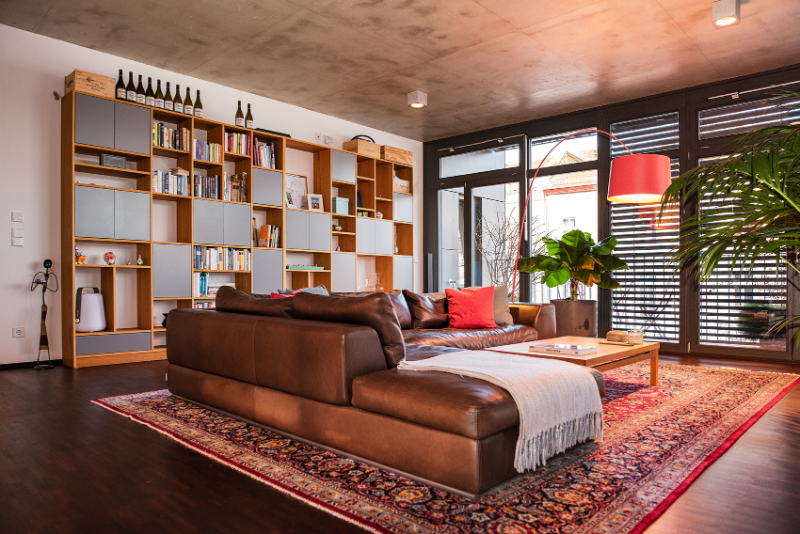 The Best Interior Designers of Germany, th einner house living room with a brown sofa and a wood bookcase